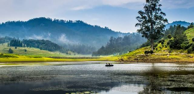 Kodaikanal lake with a boat and misty hills